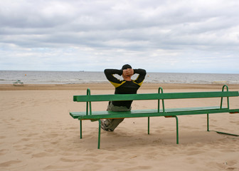 alone man on bench looking at the sea in Latvia