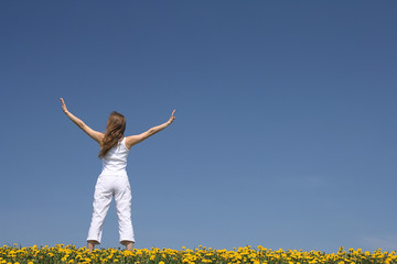 Young woman exercising outdoors, in a flowering field.