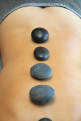 Treatment of hot stones massage. Young girl relaxing.