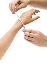 Two male hands puting a diamonds strap in a woman's arm
