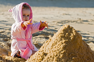 Child reaching for a sand on the beach