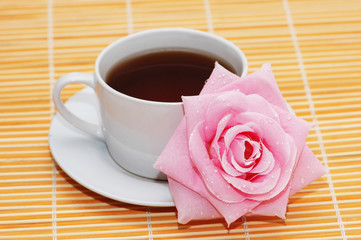 Cup of black tea and rose on  orange mat