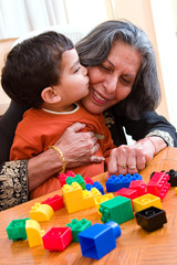 A child plays kisses his grandmother while playing with his toys