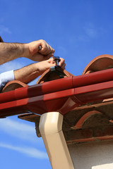 Man installing pvc rain gutter system on a house