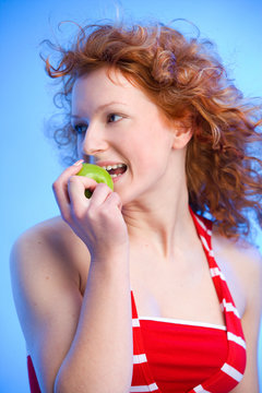 wunderschönes rothaariges Mädchen beißt in einen grünen Apfel