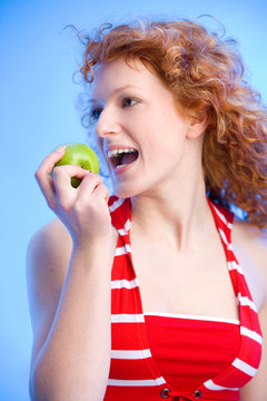 wunderschönes rothaariges Mädchen beißt in einen grünen Apfel