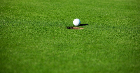 Golf ball by the hole in putting green