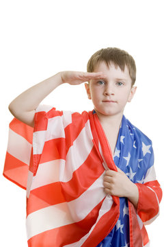 A boy wraped in american flag saluting