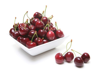 Naklejka na ściany i meble A filled bowl of cherries over white