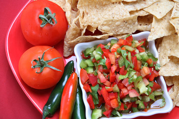 Nacho chips on a plate with salsa and vegetables