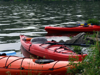 Three touring kayaks beached on the edge of the Potomac River.