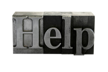 old, inkstained metal type letters form the word 'Help'