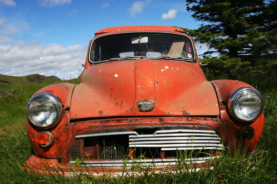 a rusty old car sitting on the ground on a farm in Iceland
