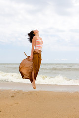 happy young woman is jumping in beach.