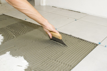 La pose du carrelage par le carreleur.