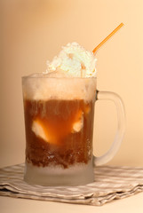 A root beer float in frosted glass and straw