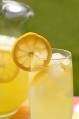 A pitcher and a glass of lemonade with lemon slices