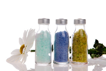 Spa bottles with salt on white background