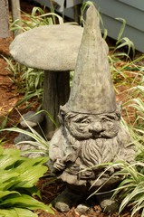 A concrete garden gnome sitting in a garden