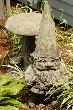 A Concrete Garden Gnome Sitting In A Garden