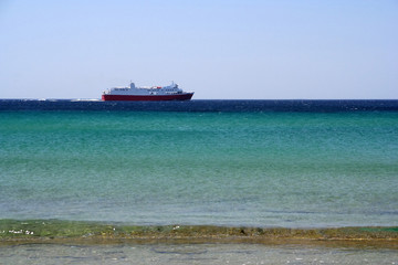 A ferry boat - seen from the beach - sailing to its destination