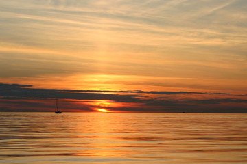 Sunset with a sailing yacht and water reflection