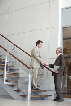Businessmen shaking hands on steps