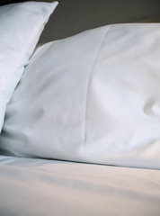 Fototapeta na wymiar Starched White Pillows on Cozy Bed
