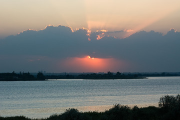 sunset on the river with clouds and sun rays