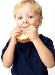 Boy taking a big bite of its peanut butter sandwich