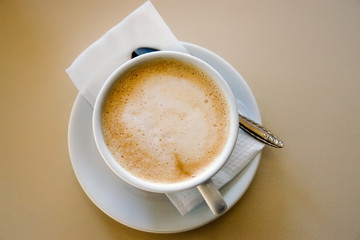flat white coffee on saucer with serviette
