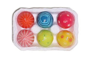 Colorful Easter candle eggs in a carton over white
