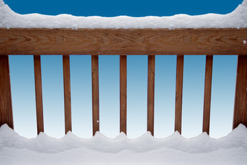 snow gracing a deck railing over a blue background
