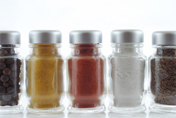 Five spice jars in a row on white background..