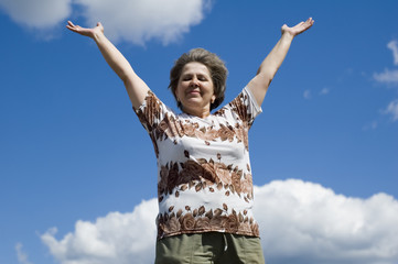woman with hand up on blue sky and clouds