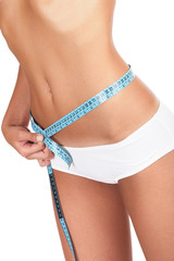 Beautiful woman measuring her waist - high key shot in studio