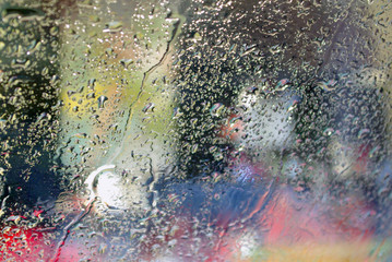 Colorful background with raindrops on a windshield of a car
