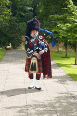 A Scottish bagpiper in full highland kilt dress and beard 