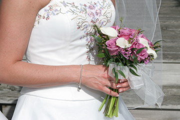 Obraz na płótnie Canvas flower bouquet in hands with elegant white dress gown