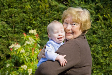 Naklejka na ściany i meble Grandmother hugging happy grandson in sunny garden