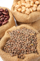 Burlap sack with lentils over a white background. Shallow DOF