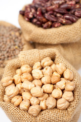 Burlap sack with chickpeas over a white background. Shallow DOF