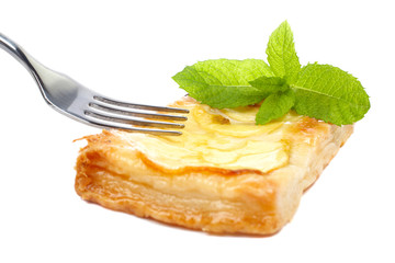 Fork and apple tart with leaves of mint on a dish. Soft shadow