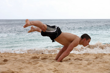 Young man doing handstand on the beach