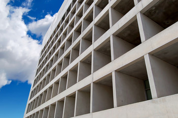 A modern concrete building with blue sky and clouds