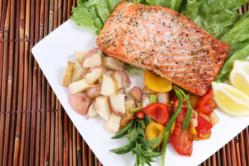 A baked salmon dinner with vegetables and potatoes