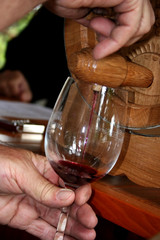 Red wine being poured in to a wine glass from a small barrel