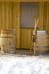 Antiquated pair of skis leaning against a wooden barrel