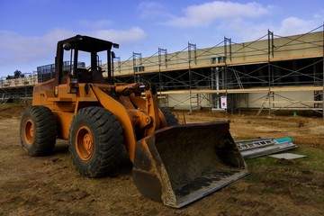 Earth mover in front of scaffolding for a new parking lot 