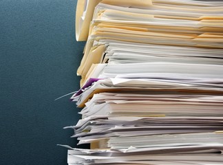 Pile of paperwork against a textured green cubicle wall